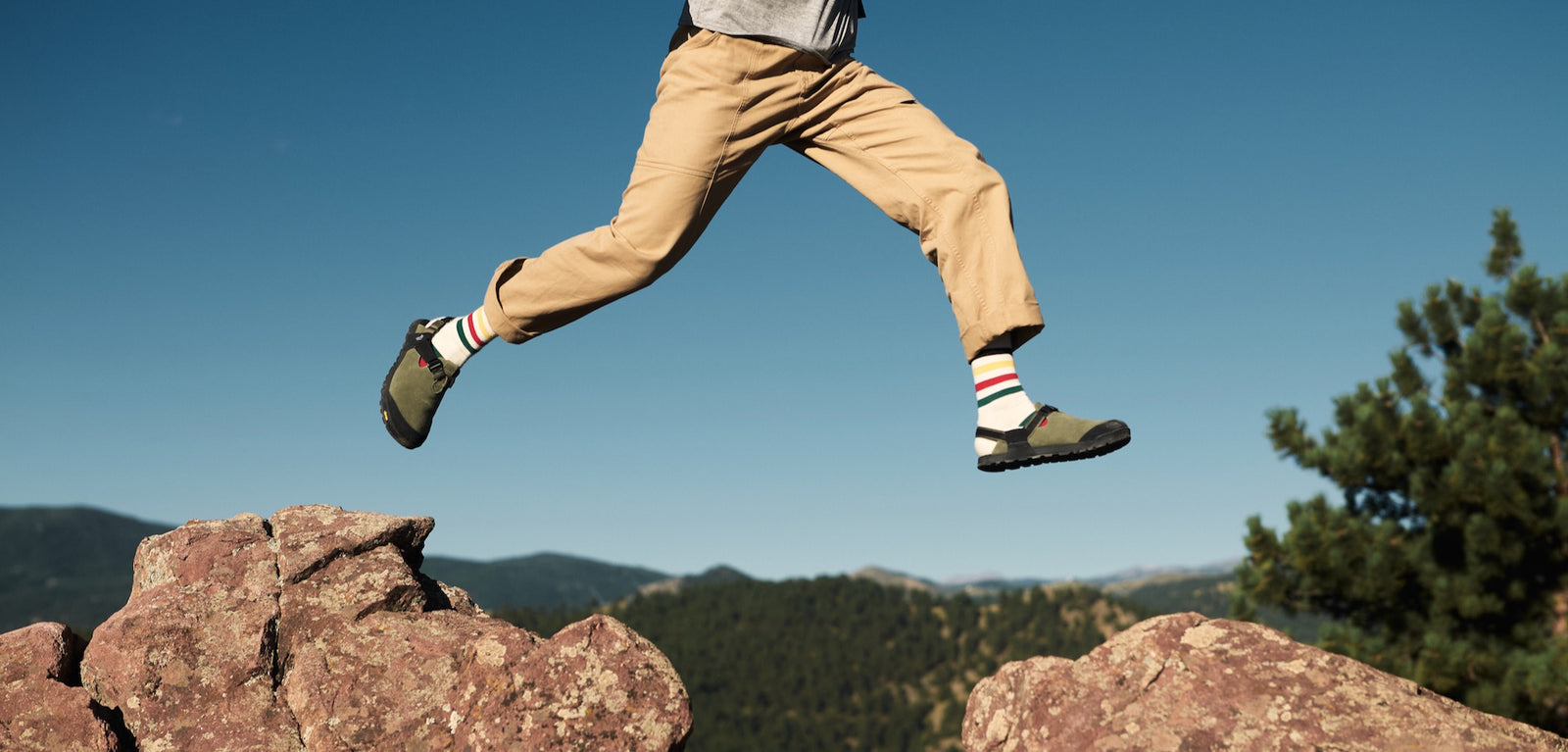 Person jumping between rocks earing mountain clogs