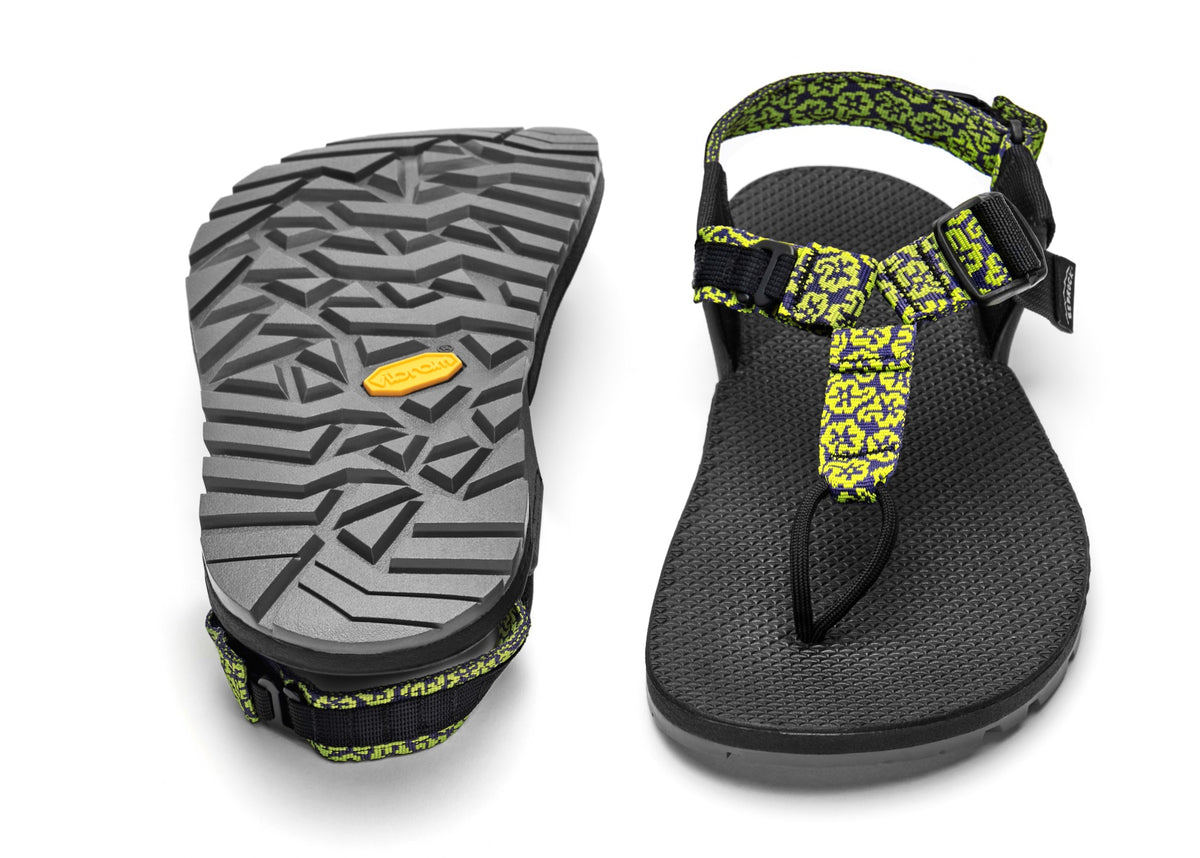 A pair of Cairn Evo PRO Sandals with yellow wildflower patterned straps and black footbed, featuring a hook-and-loop strap design and Vibram Megarip outsole.