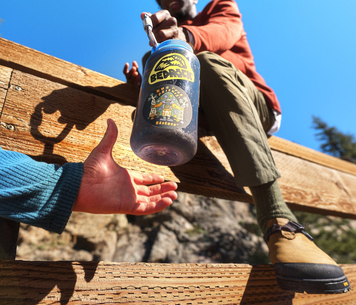Bedrock die cut stickers stuck on a nalgene bottle being passed friend to friend