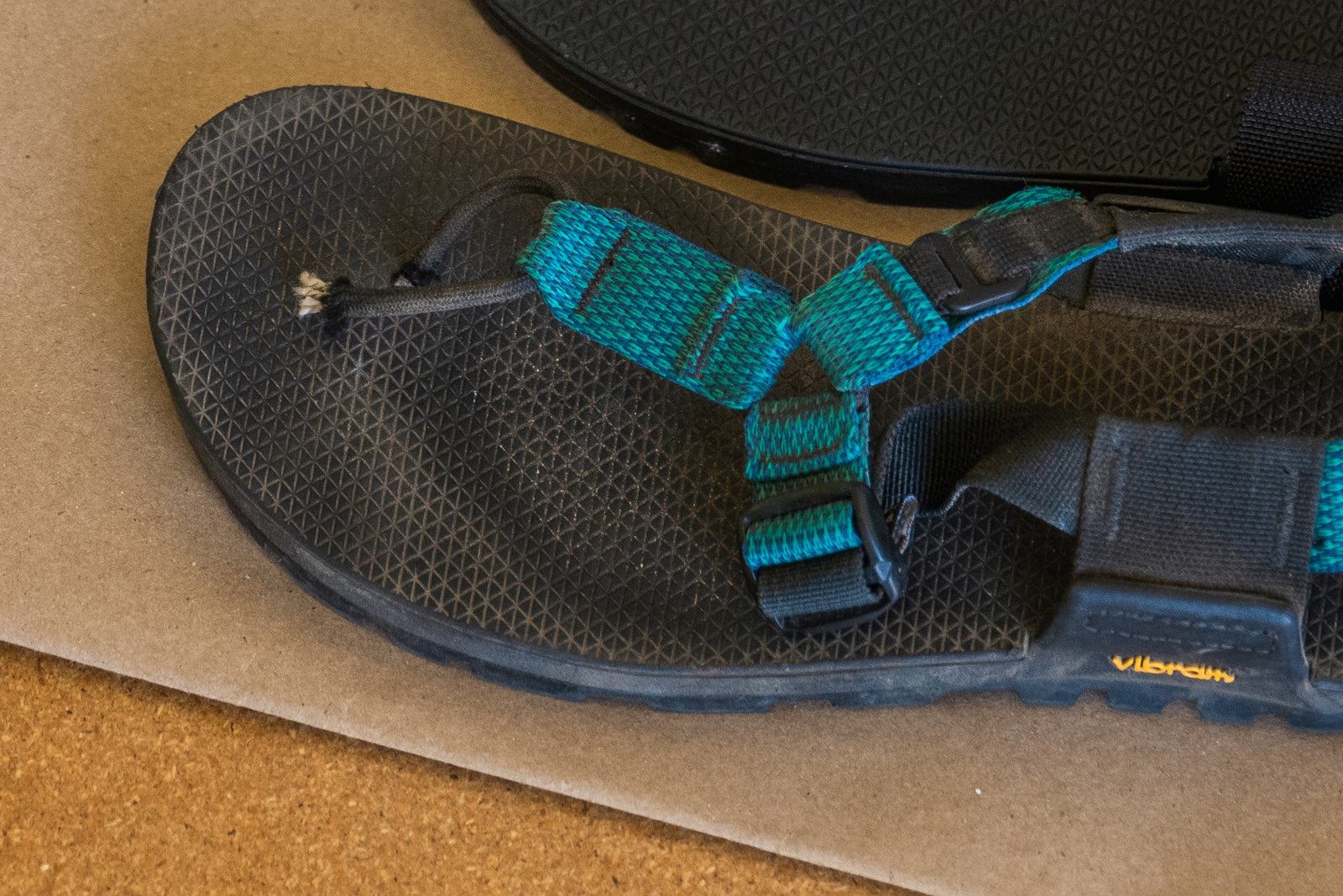 Black sandal with teal straps and broken toe post strap