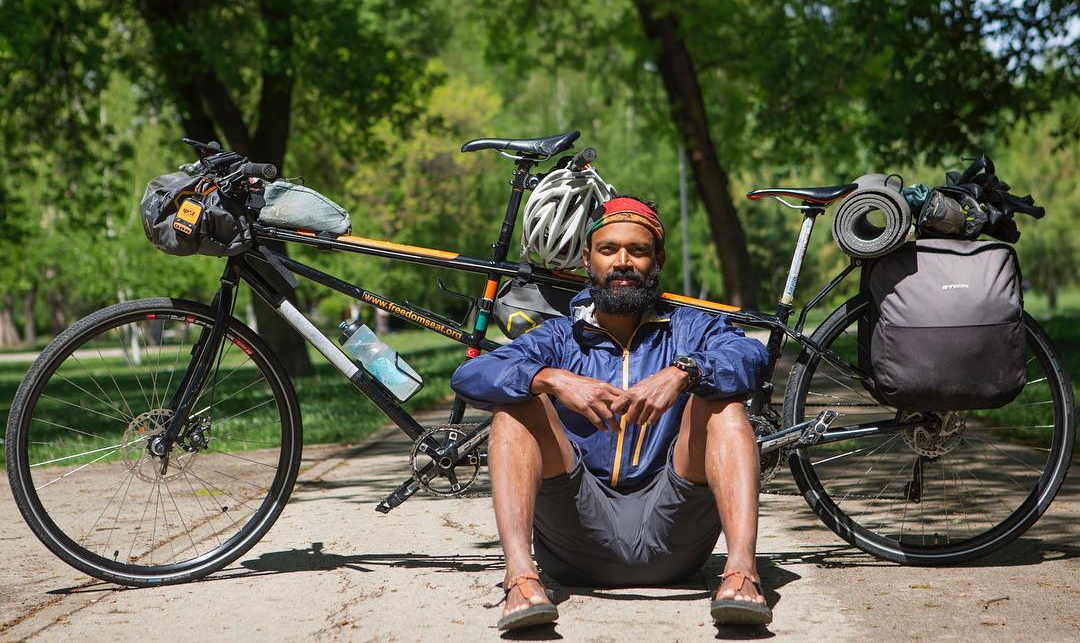 Naresh Kumar sitting in Bedrock Sandals by his tandem bike
