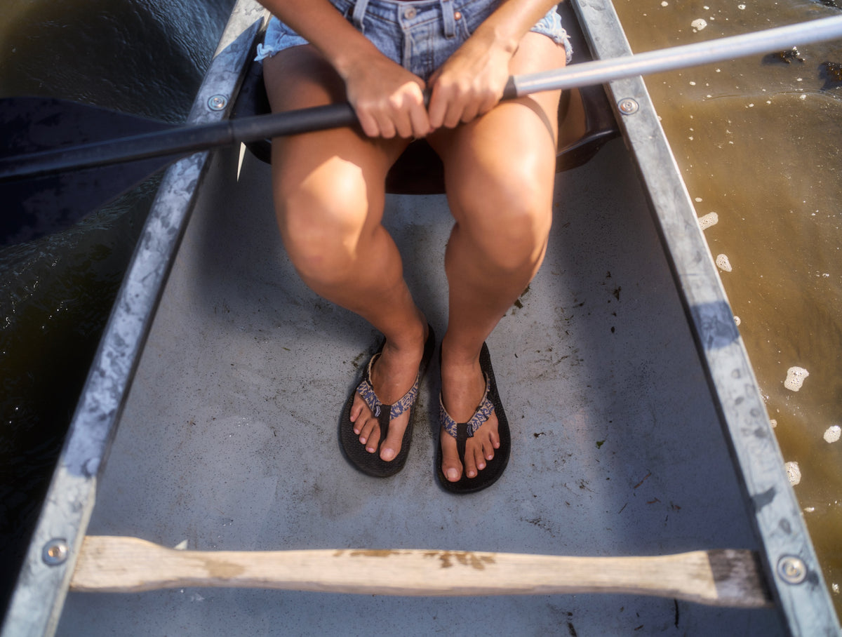Person rowing a boat with focus on legs and oar.