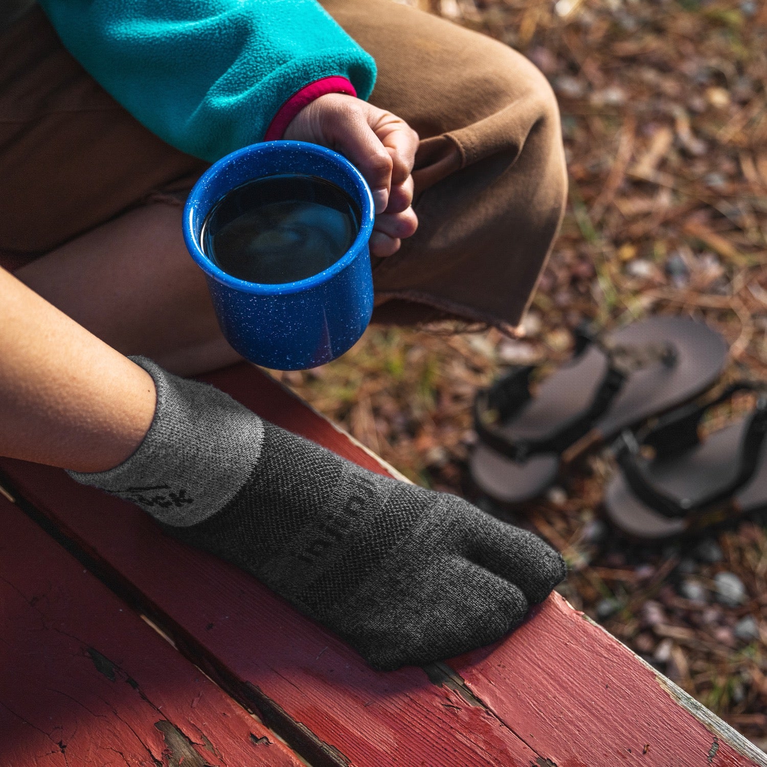 Person wearing Bedrock Split-Toe Socks while drinking coffee on picnic table