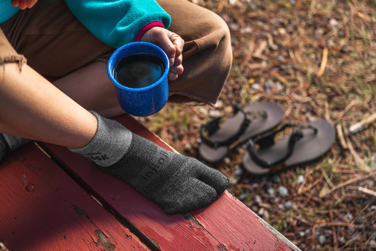 Person wearing Bedrock Injinji Split-Toe Performance Socks Granite on picnic table with coffee